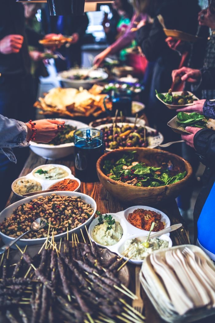 Services A vibrant buffet spread with salads, skewers, and dips at a lively indoor gathering.