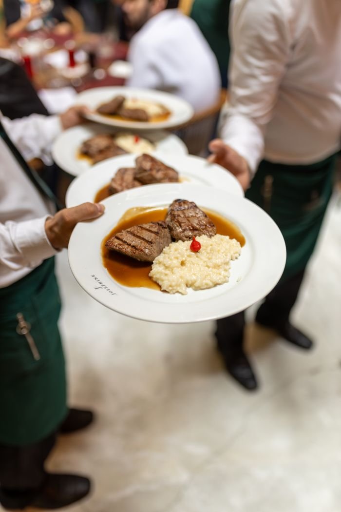 Waiters serving gourmet steak dishes at a fine dining restaurant.