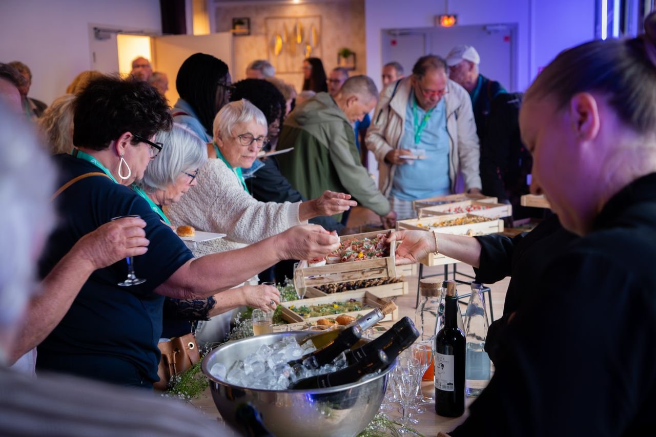 About A lively gathering of people enjoying a buffet with various food items at an indoor social event.